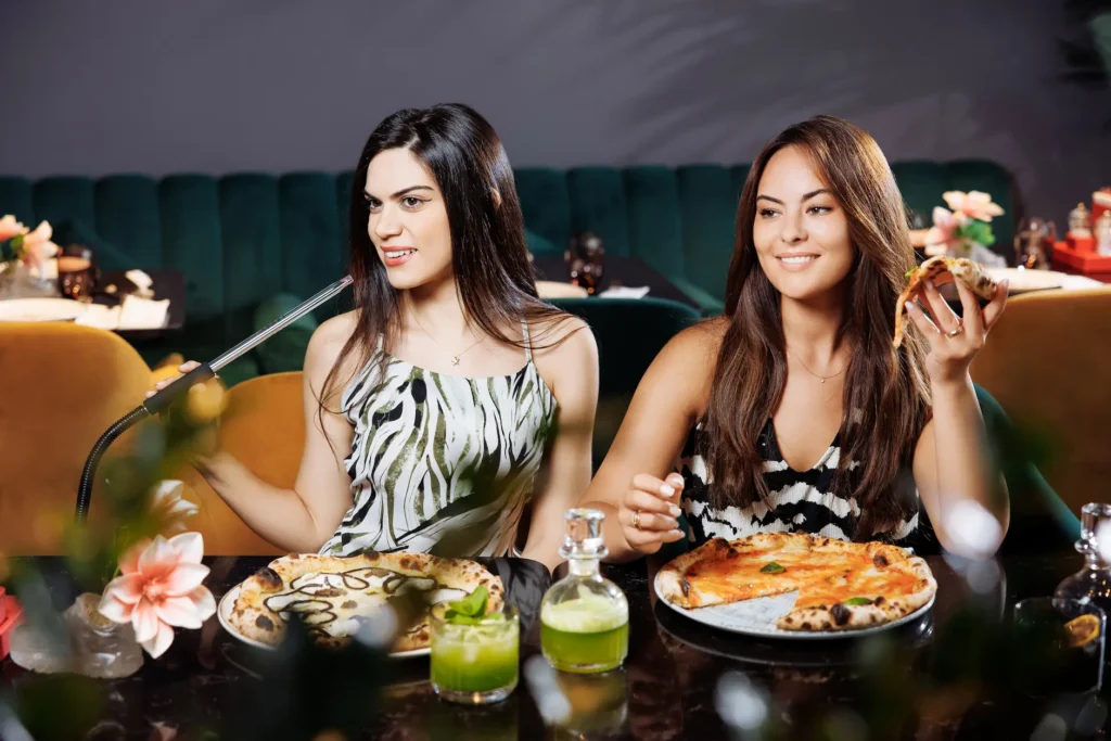 two women enjoying a shisha and pizza