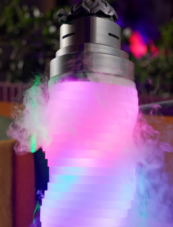 The shisha setup with clouds of smoke around with pink, green, and blue lights