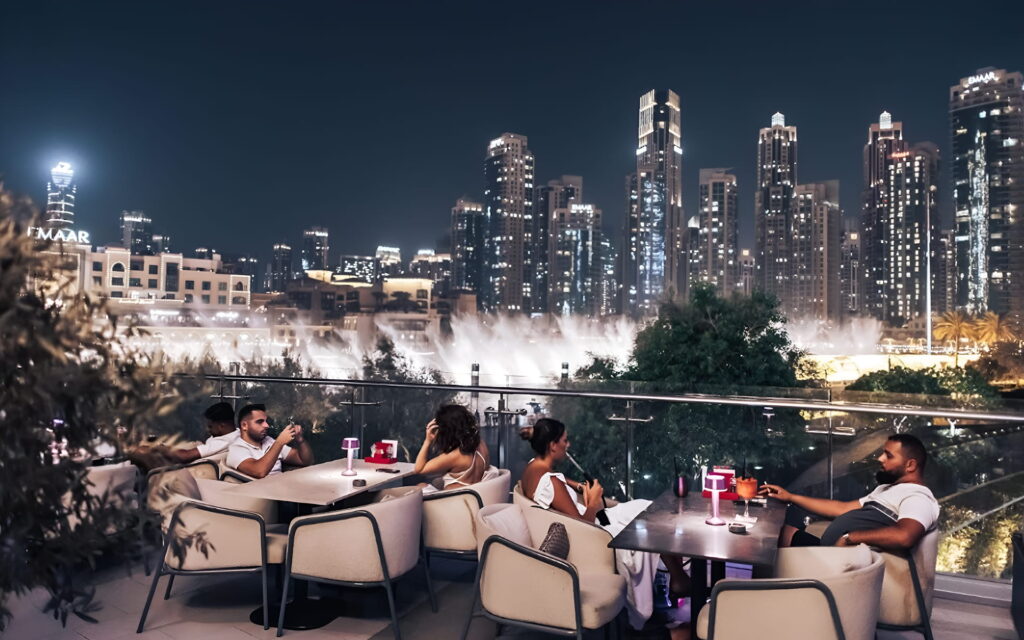 People dining on an outdoor terrace in downtown Dubai at night with a view of the city skyline