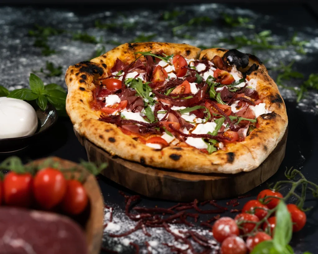 Pizza Margaritha on a table with cherry tomatoes