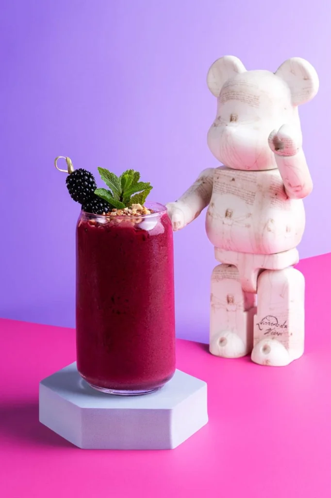Dark pink smoothie with mint leaves and berries with teddy on the side