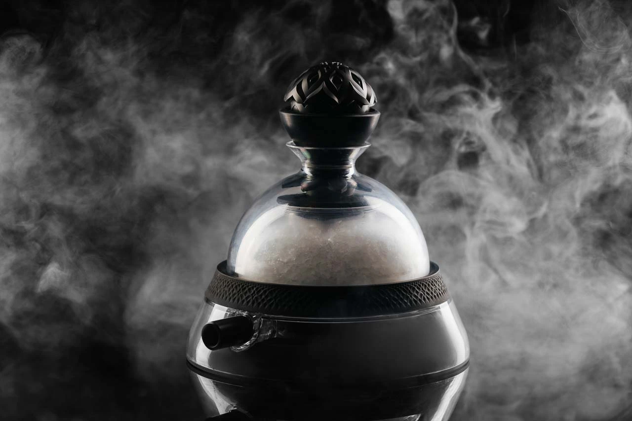 The top of a black shisha with smoke in the background