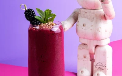 Dark pink smoothie with mint leaves and berries with teddy on the side