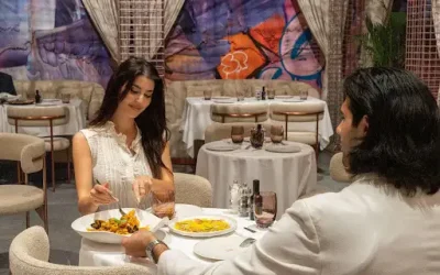 Couple sharing a private dining table at Trove in Dubai Mall, with seafood pasta and street art behind them